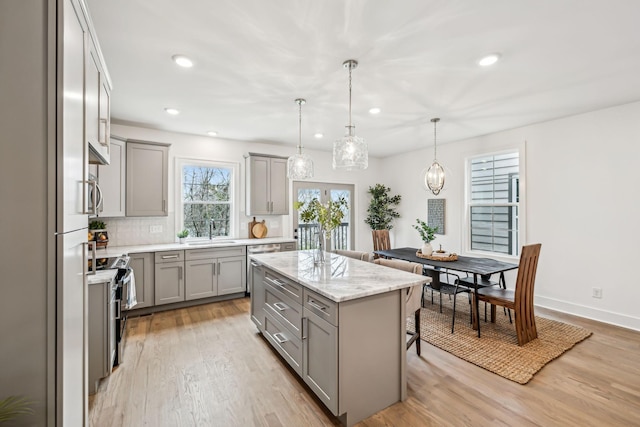 kitchen with gray cabinetry, a breakfast bar area, a sink, and light wood-style floors