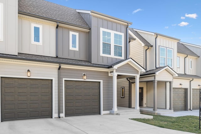 townhome / multi-family property with driveway, a garage, board and batten siding, and roof with shingles
