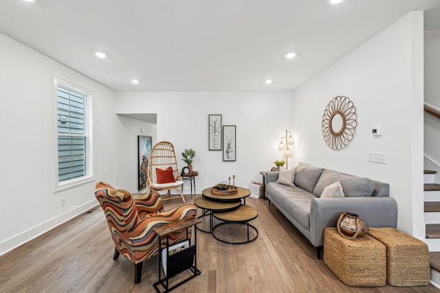 living area with baseboards, wood finished floors, recessed lighting, and stairs