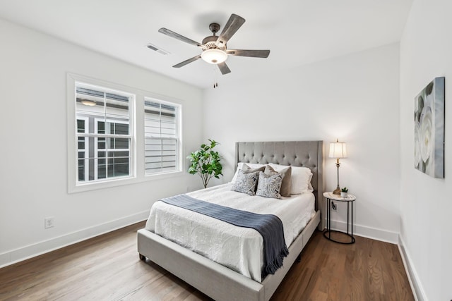 bedroom featuring wood finished floors, baseboards, ceiling fan, and visible vents