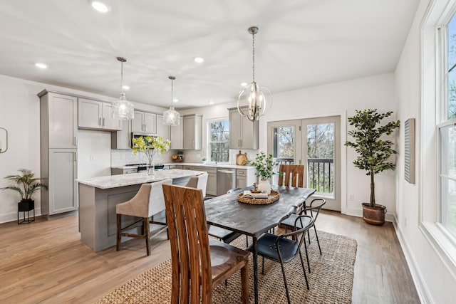 dining room with baseboards, light wood-style flooring, recessed lighting, and a notable chandelier