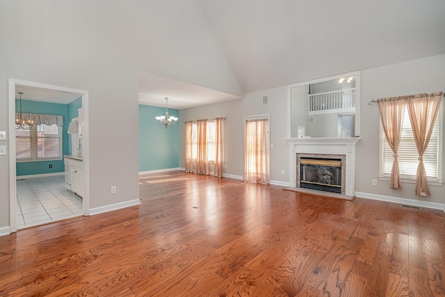 unfurnished living room with a notable chandelier, a healthy amount of sunlight, a fireplace, and wood finished floors