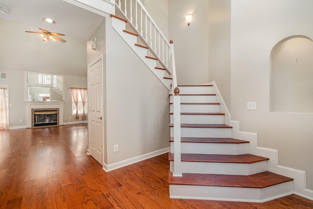 stairway with visible vents, wood finished floors, baseboards, and arched walkways