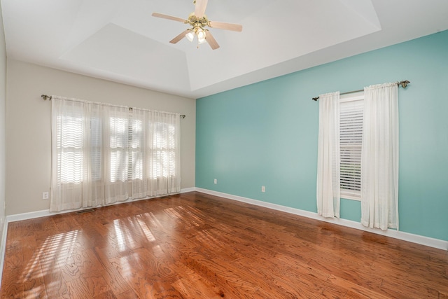 spare room featuring baseboards, a raised ceiling, a ceiling fan, and wood finished floors