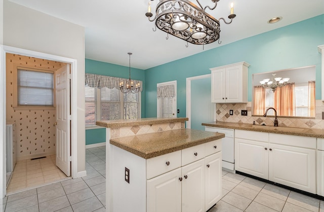 kitchen with a sink, backsplash, a center island, white dishwasher, and a chandelier