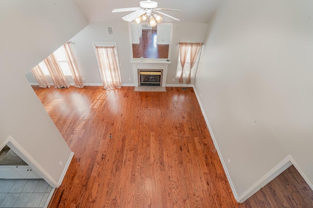 unfurnished living room with baseboards, wood finished floors, visible vents, and ceiling fan
