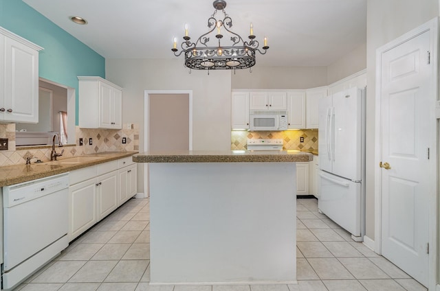 kitchen with a kitchen island, light tile patterned floors, white cabinets, white appliances, and a sink