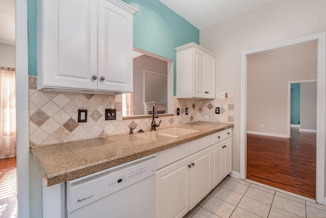 kitchen featuring white cabinetry, light tile patterned flooring, a sink, decorative backsplash, and dishwasher