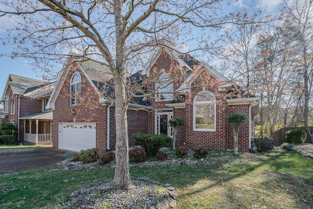 view of front of house featuring aphalt driveway, brick siding, a garage, and a front yard