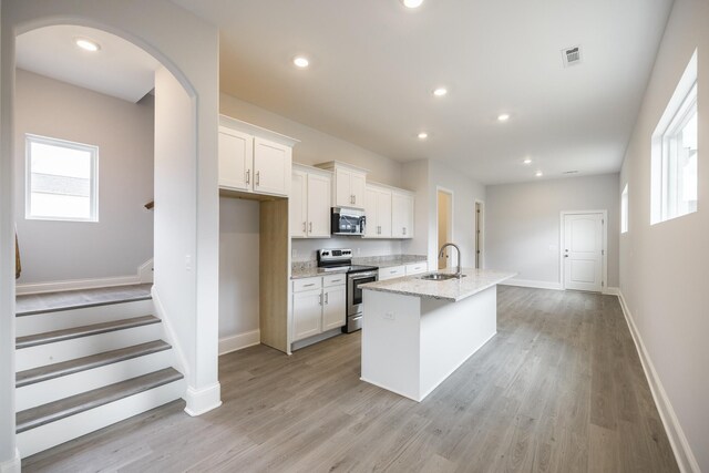 158 Oasis Dr, La Vergne, TN 37086 - kitchen featuring visible vents, an island with sink, light wood-type flooring, appliances with stainless steel finishes, and white cabinetry