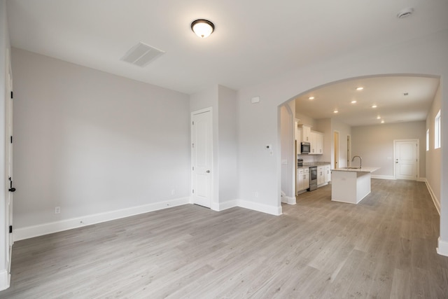 158 Oasis Dr, La Vergne, TN 37086 - unfurnished living room with visible vents, baseboards, recessed lighting, arched walkways, and light wood-style floors