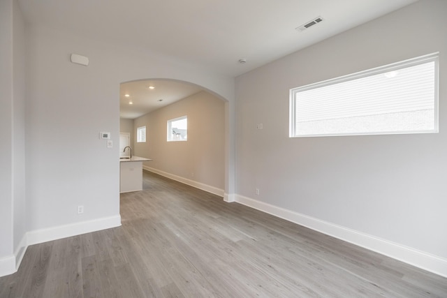 158 Oasis Dr, La Vergne, TN 37086 - empty room featuring visible vents, baseboards, light wood-style flooring, recessed lighting, and arched walkways