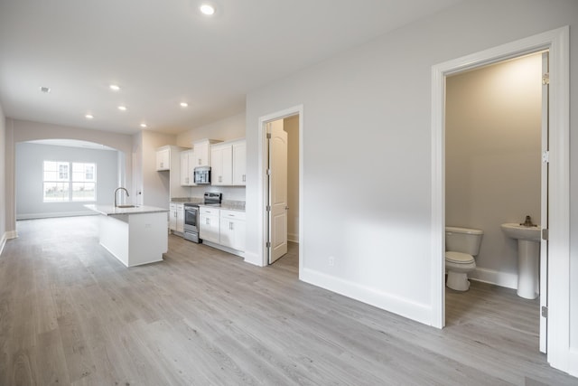 158 Oasis Dr, La Vergne, TN 37086 - kitchen featuring appliances with stainless steel finishes, light wood-style floors, arched walkways, white cabinets, and a sink