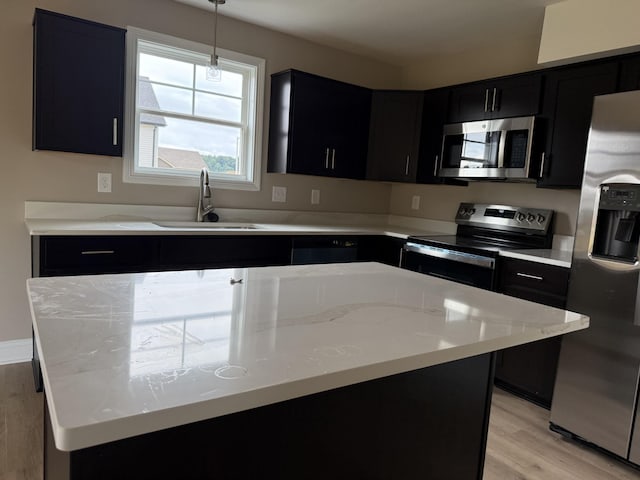180 Cardinal Crk, Clarksville, TN 37040 - kitchen with appliances with stainless steel finishes, dark cabinetry, a sink, light wood-type flooring, and hanging light fixtures
