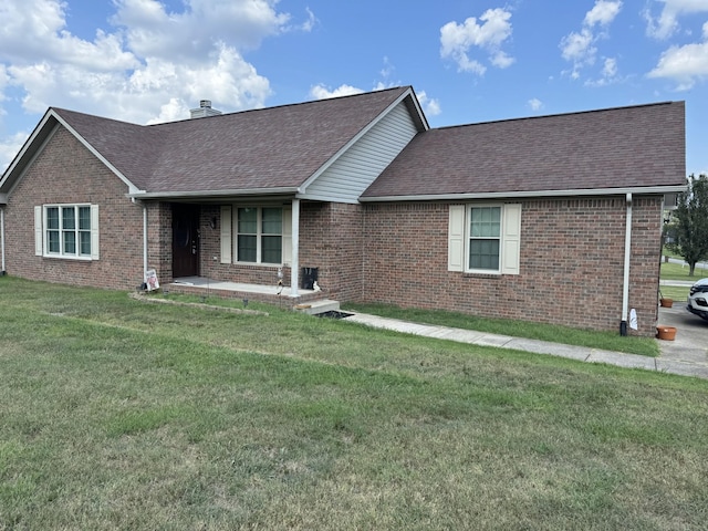 ranch-style house featuring a front yard, brick siding, roof with shingles, and a chimney