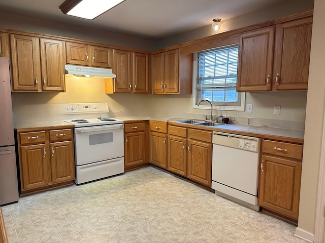 kitchen with under cabinet range hood, a sink, white appliances, brown cabinetry, and light floors