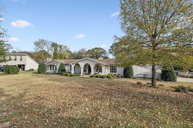 ranch-style house featuring covered porch, stucco siding, a chimney, and a front yard