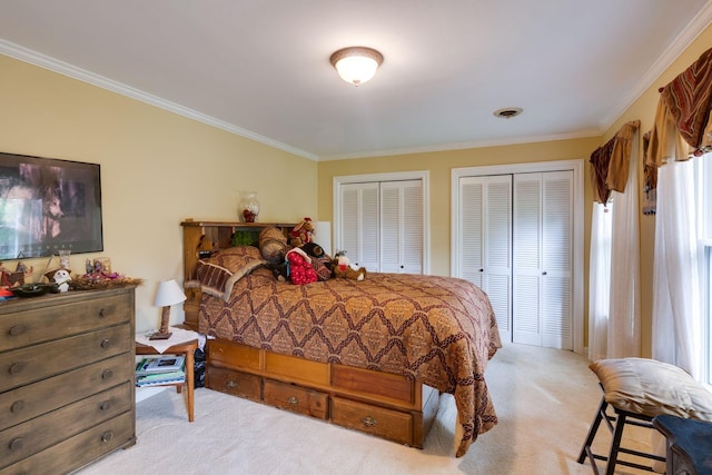 carpeted bedroom featuring visible vents, crown molding, and multiple closets
