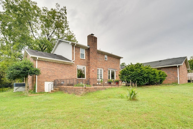 rear view of property featuring a yard, brick siding, and a chimney