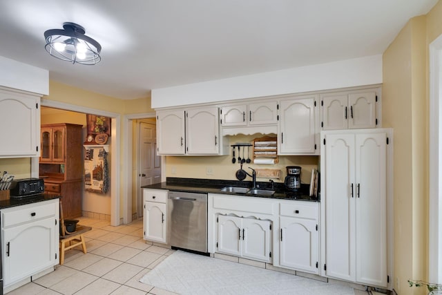 kitchen featuring stainless steel dishwasher, white cabinets, light tile patterned flooring, and a sink
