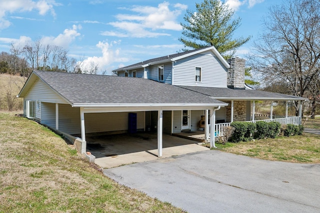 farmhouse-style home with a front lawn, driveway, roof with shingles, covered porch, and a carport