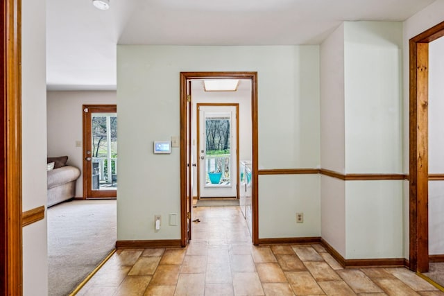 hallway featuring baseboards and light colored carpet
