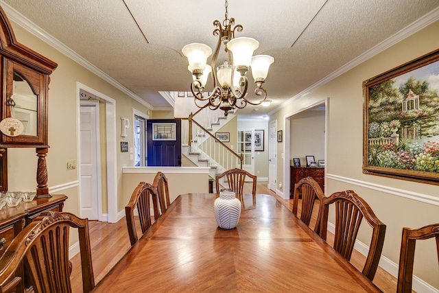 dining room featuring a textured ceiling, wood finished floors, an inviting chandelier, crown molding, and stairs