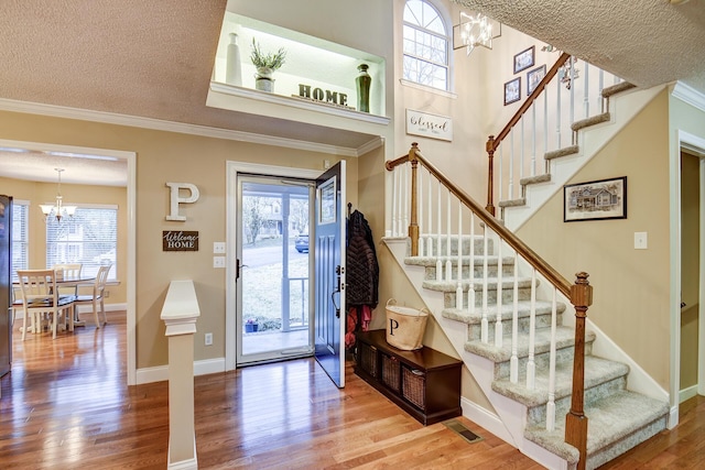 entryway featuring wood finished floors, stairway, a healthy amount of sunlight, and a chandelier