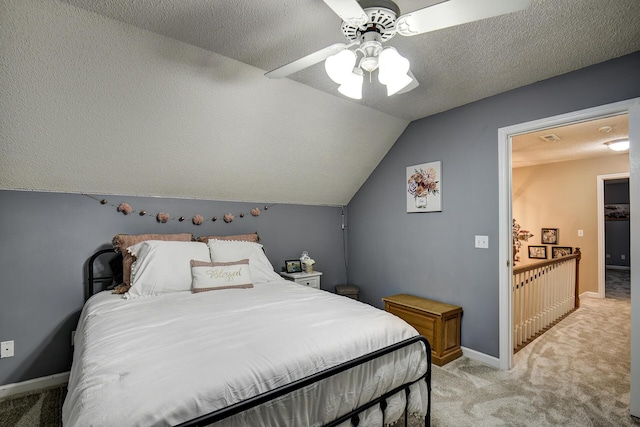 bedroom with a ceiling fan, a textured ceiling, baseboards, light colored carpet, and vaulted ceiling