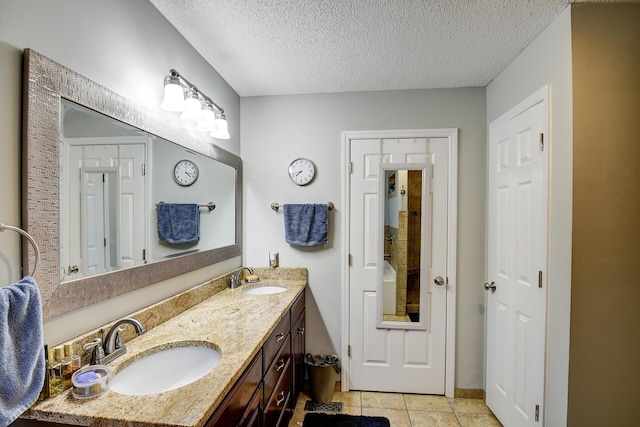 bathroom with tile patterned floors, double vanity, a textured ceiling, and a sink
