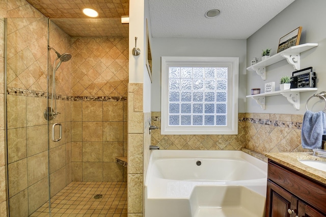 full bath featuring a textured ceiling, a stall shower, vanity, and a bath