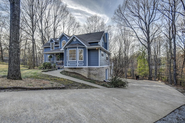 view of front facade with roof with shingles, a porch, and driveway