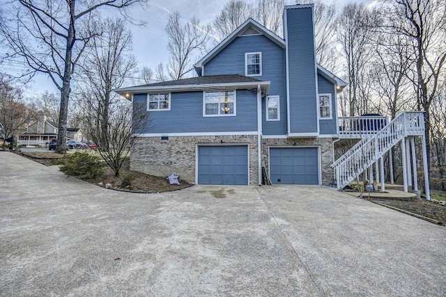view of side of property featuring stairs, concrete driveway, a garage, and a chimney