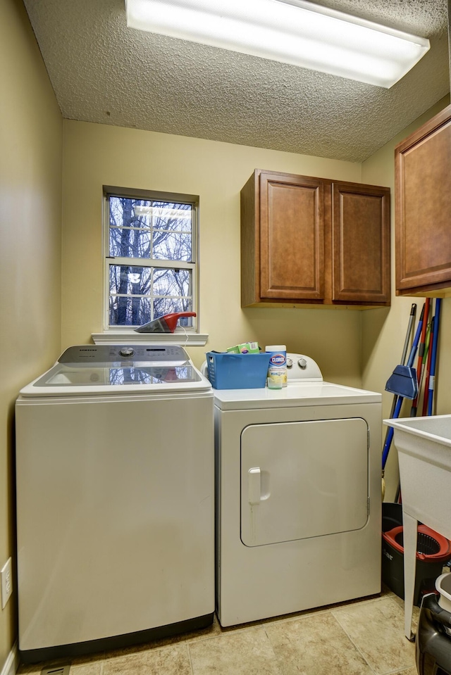 washroom featuring cabinet space, washer and dryer, a textured ceiling, and a sink