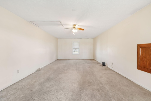 empty room with light carpet, attic access, and a ceiling fan