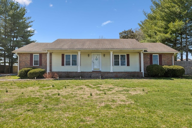 ranch-style home with brick siding, a shingled roof, a front lawn, and fence