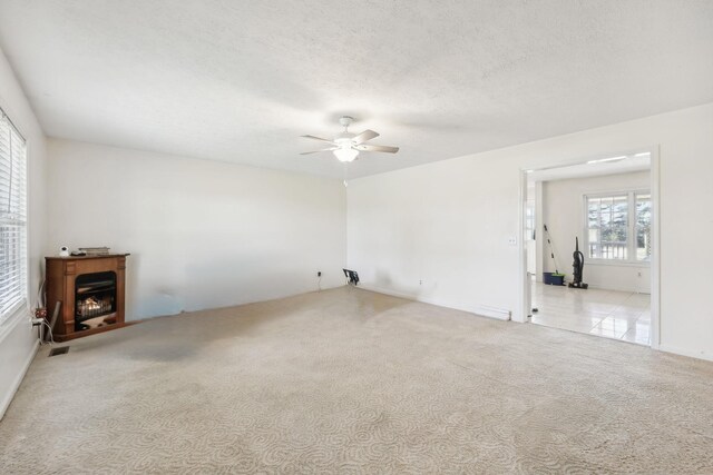 unfurnished room with a textured ceiling, ceiling fan, and carpet flooring
