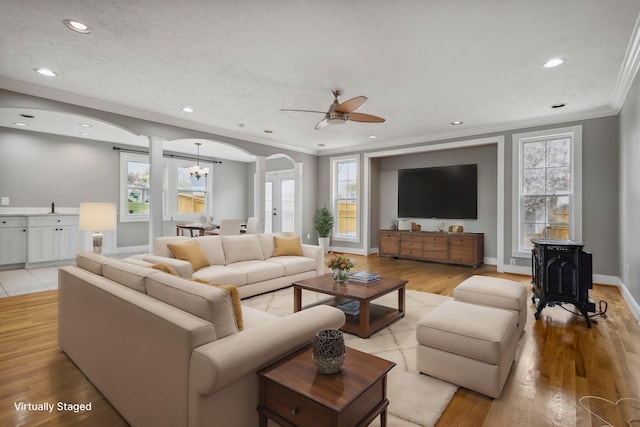 living area with light wood-style flooring, recessed lighting, arched walkways, and ornamental molding