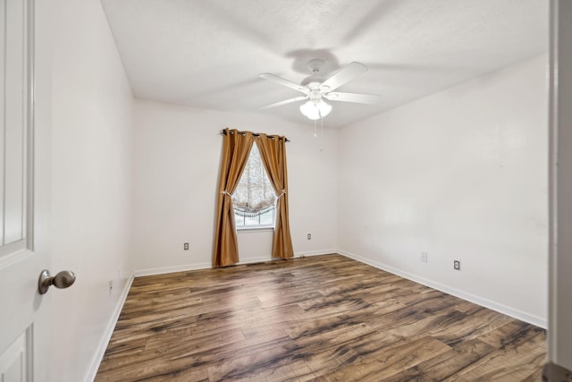 empty room with baseboards, wood finished floors, ceiling fan, and a textured ceiling