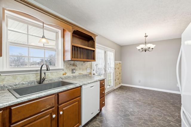 kitchen with plenty of natural light, white appliances, a notable chandelier, and a sink
