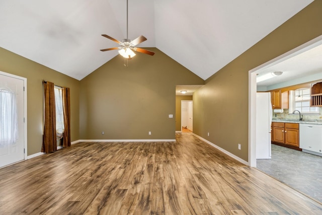 unfurnished living room with vaulted ceiling, baseboards, a sink, ceiling fan, and wood finished floors