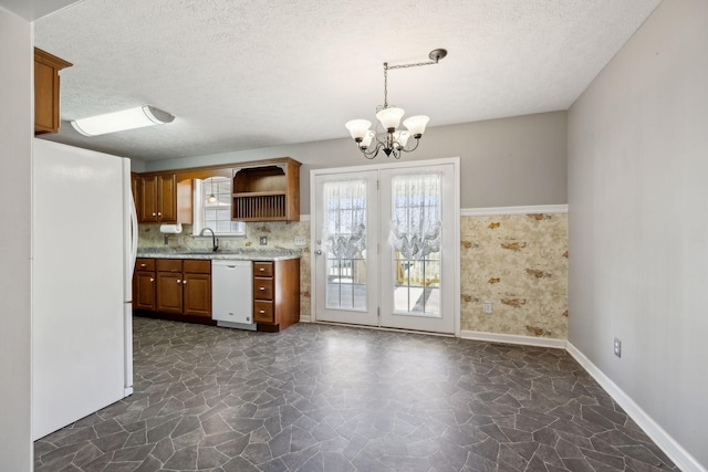 kitchen with a sink, open shelves, a chandelier, brown cabinets, and white appliances