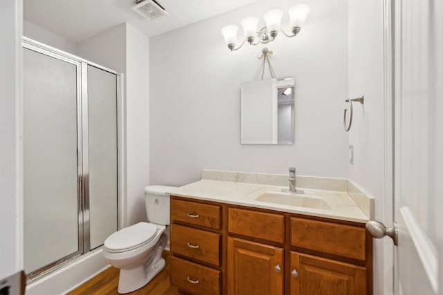 bathroom featuring visible vents, a stall shower, toilet, and vanity