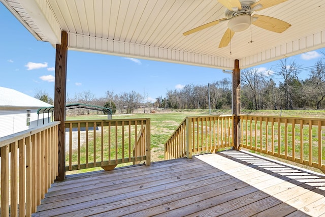wooden terrace featuring a ceiling fan and a yard