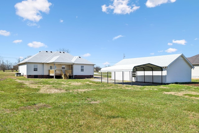 rear view of property featuring driveway, a carport, and a yard