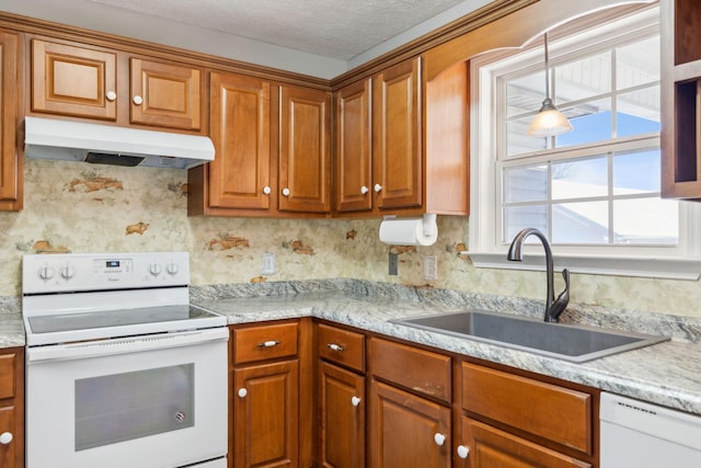 kitchen featuring under cabinet range hood, a sink, brown cabinets, and white appliances