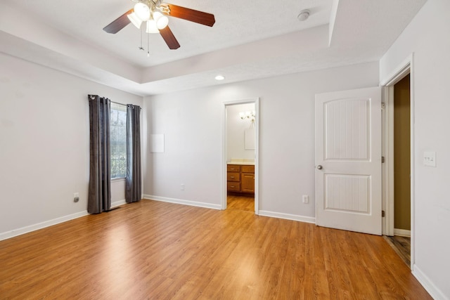 unfurnished bedroom with light wood-style flooring, ensuite bath, baseboards, and ceiling fan