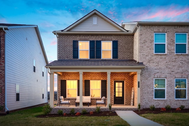 view of front of house with brick siding, covered porch, and a front lawn