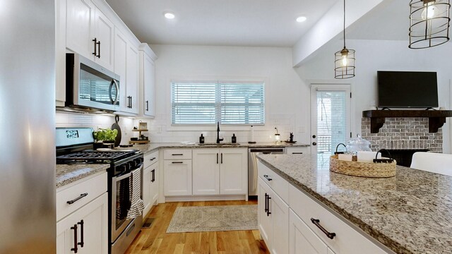 5020 E Mayflower Ct, Greenbrier, TN 37073 - kitchen featuring light stone counters, light wood finished floors, a sink, stainless steel appliances, and tasteful backsplash