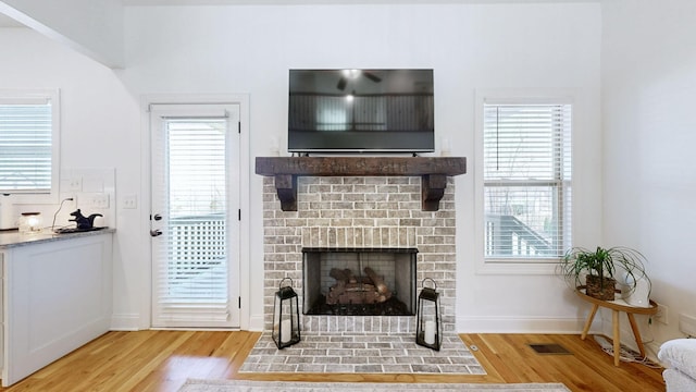 5020 E Mayflower Ct, Greenbrier, TN 37073 - living area featuring visible vents, a brick fireplace, baseboards, and wood finished floors